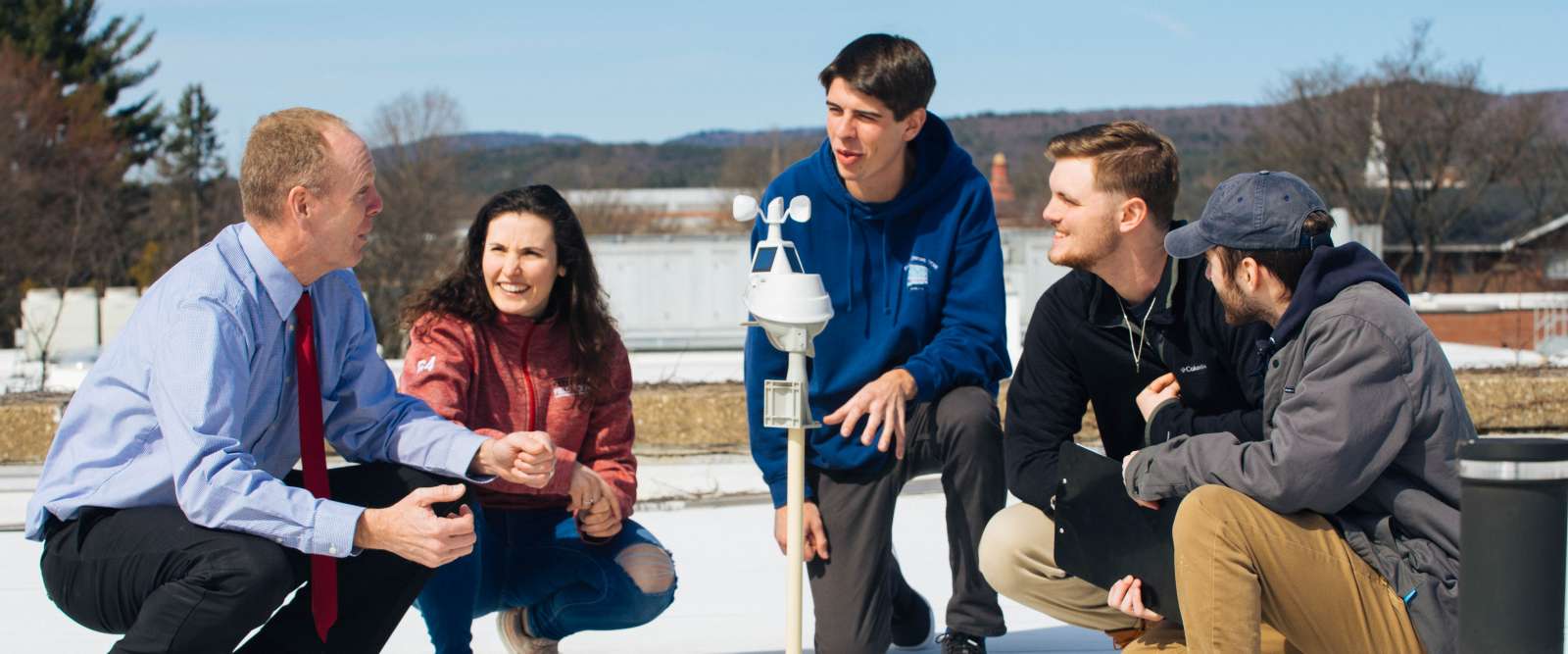 Professor Chris Cusack, left, and his students gather around a weather station on the roof of the Science Center.
